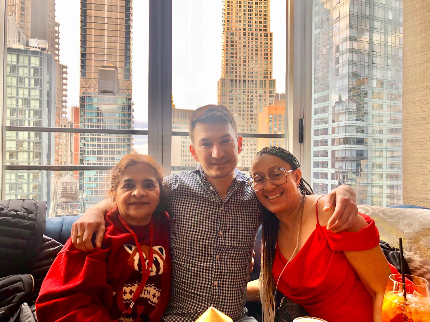 Three coworkers smiling together with the NYC skyline in the background.